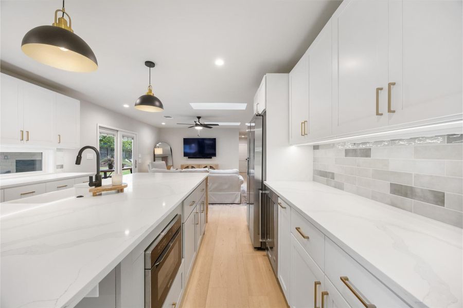 Kitchen featuring white cabinetry, open floor plan, light stone countertops, and decorative light fixtures