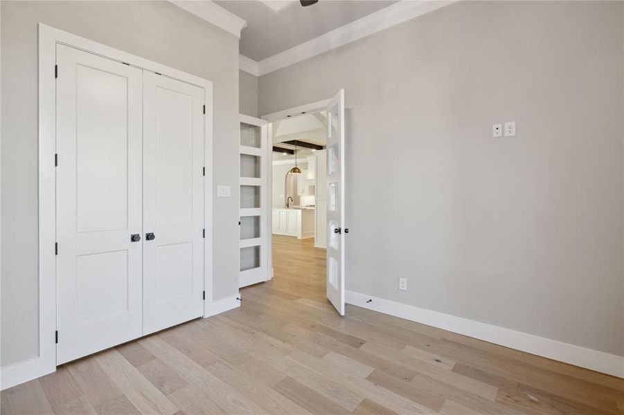 Unfurnished bedroom with sink, light wood-type flooring, crown molding, and a closet