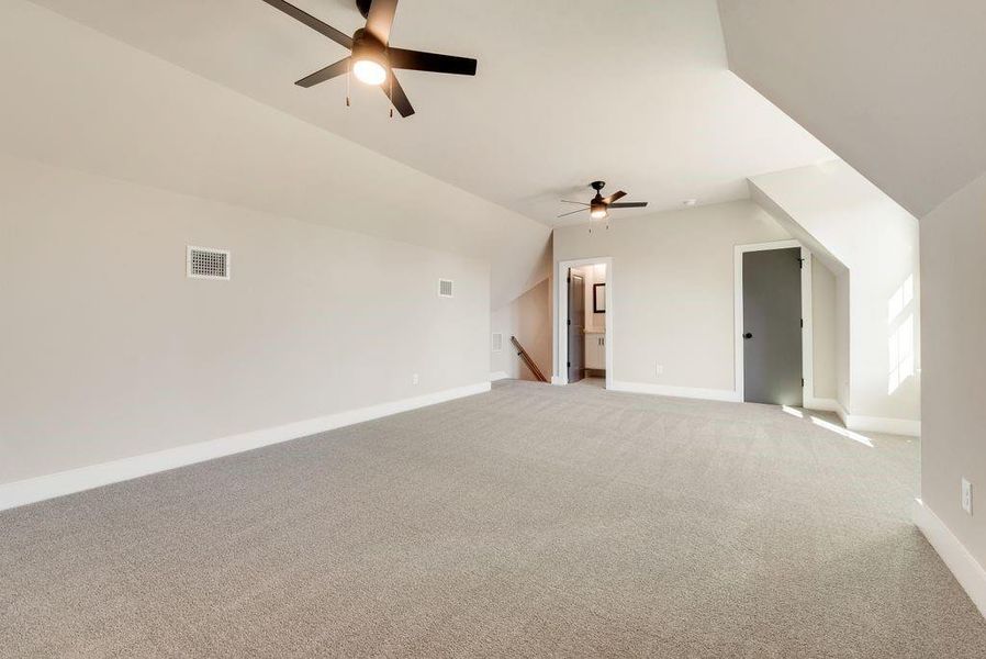 Bonus room featuring ceiling fan, light colored carpet, and lofted ceiling