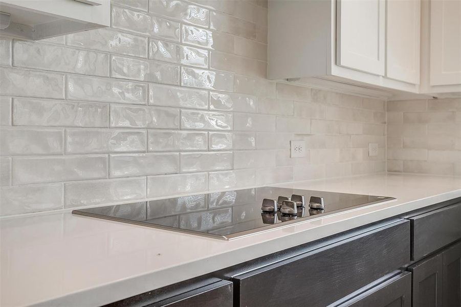 Kitchen featuring white cabinets, black electric cooktop, and tasteful backsplash