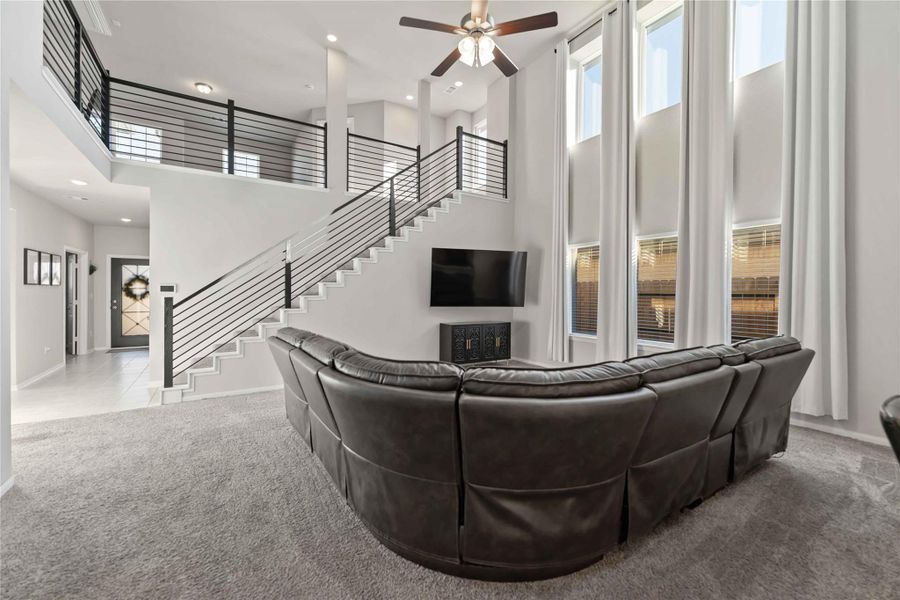 Two-story family room with soaring ceilings, dramatic iron stair rails, and a wall of windows that fill the space with natural light. Two-story family room with soaring ceilings, dramatic iron stair rails, and a wall of windows that fill the space with natural light.