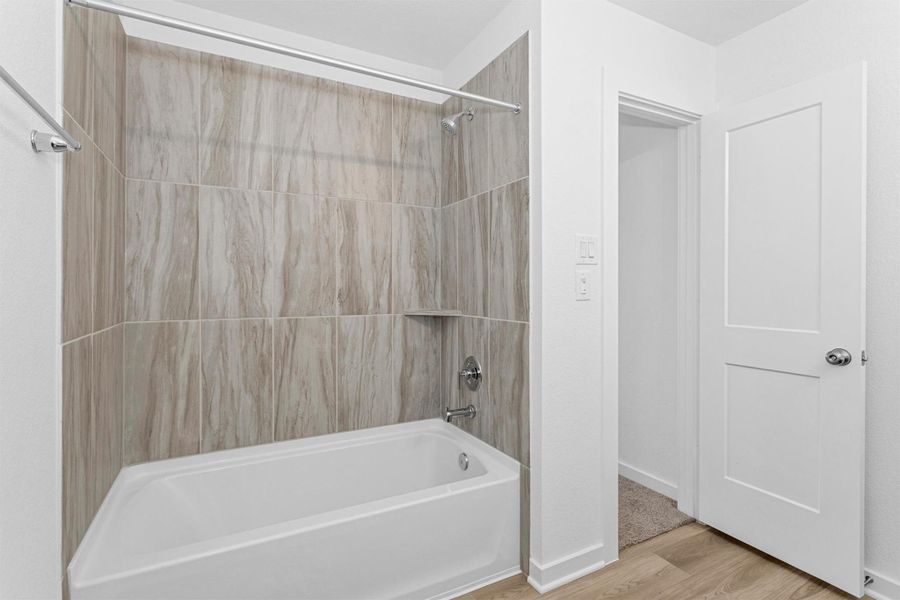 This upstairs full bathroom features a tub and shower combination with stylish tile surround, offering a clean, modern space that has never been used.