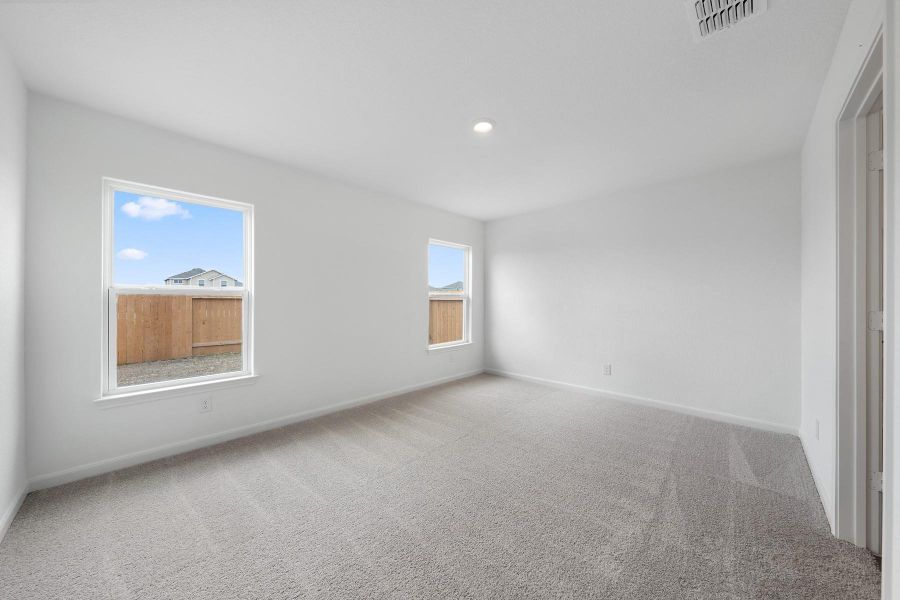 A spacious, naturally illuminated room featuring plush carpeting and modern recessed lighting.