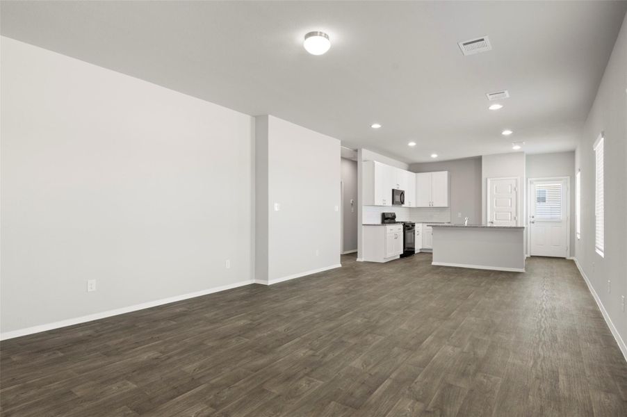 Unfurnished living room featuring recessed lighting and dark wood-type flooring