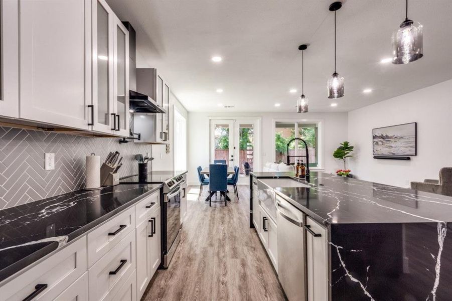 Kitchen with appliances with stainless steel finishes, backsplash, recessed lighting, light wood-style floors, and a large island