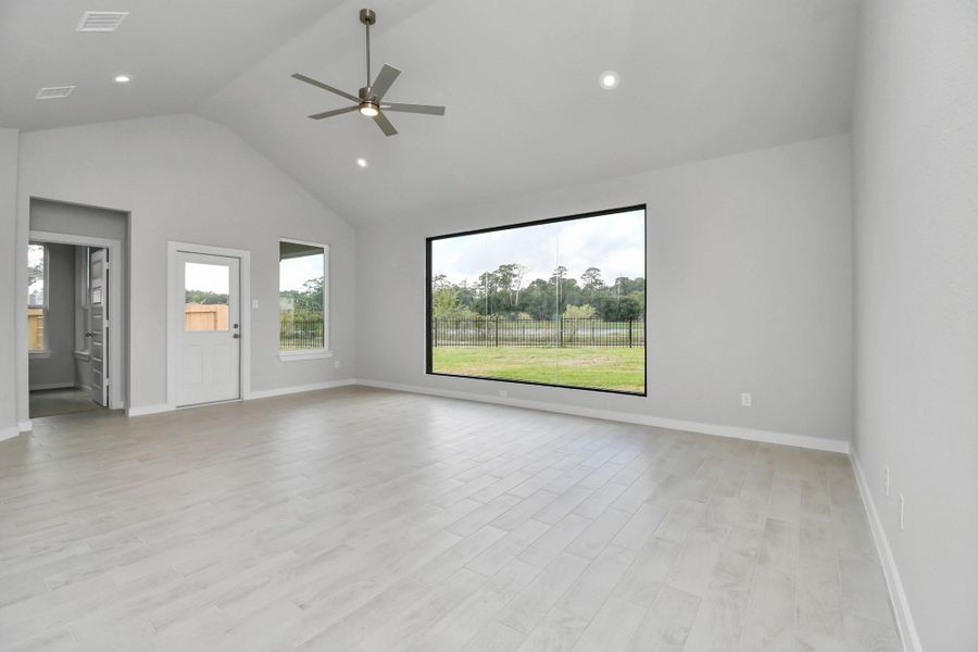 Welcome family and guests to your charming living room! With its high ceilings, recessed lighting, ceiling fan, custom paint, beautiful flooring, and large windows that let in abundant natural light, this room is perfect for gatherings. Sample photo of completed home with similar floor plan. Actual colors and selections may vary.