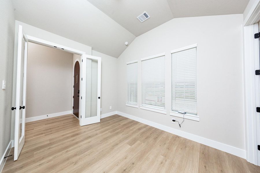 This handsome home office features tile flooring, large windows, cathedral ceilings, custom paint, walk-in closet, and gorgeous French doors for added privacy!