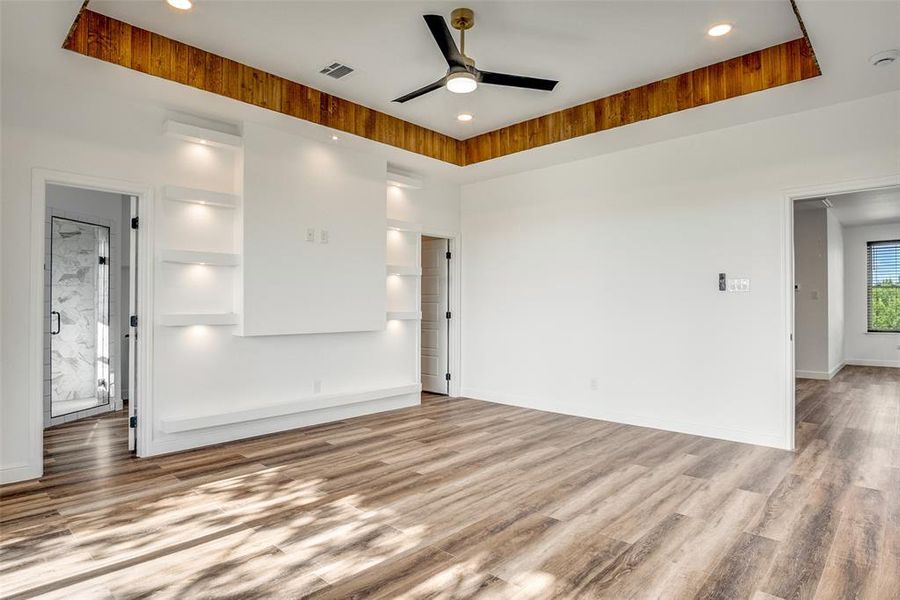 Spare room featuring a raised ceiling, light wood-style floors, ceiling fan, and recessed lighting