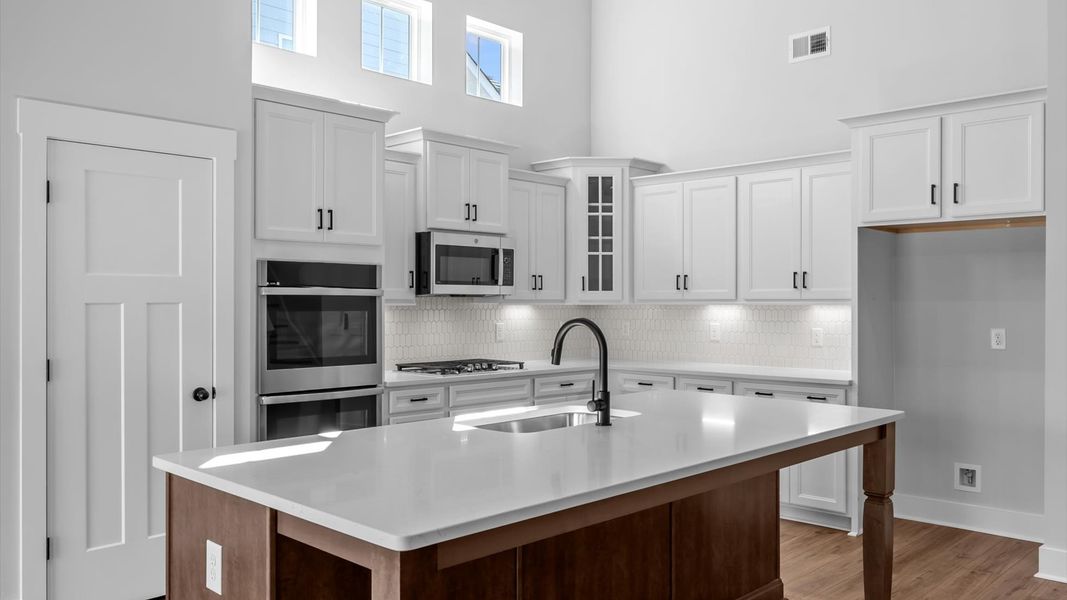 Highly skilled design choices create a clean, open kitchen with a central island