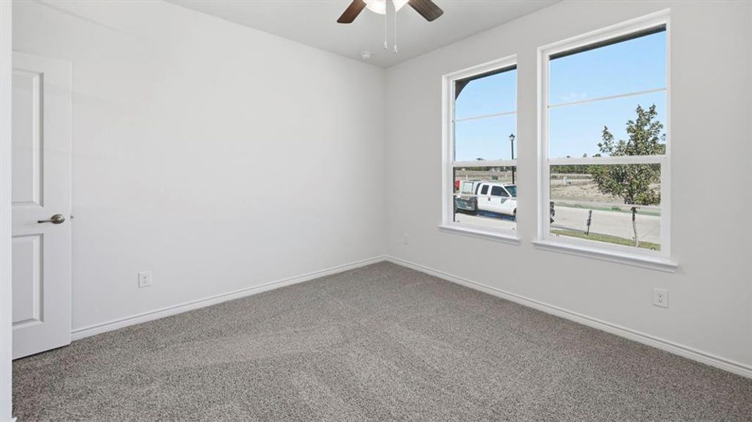 Bright room featuring two large windows, neutral carpet flooring, white baseboards, and a ceiling fan with light fixture Bright room featuring two large windows, neutral carpet flooring, white baseboards, and a ceiling fan with light fixture