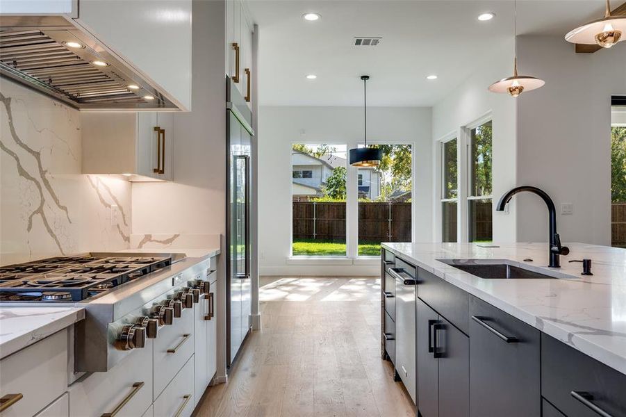 Kitchen with decorative light fixtures, under cabinet range hood, light stone countertops, stainless steel appliances, and recessed lighting Kitchen with decorative light fixtures, under cabinet range hood, light stone countertops, stainless steel appliances, and recessed lighting