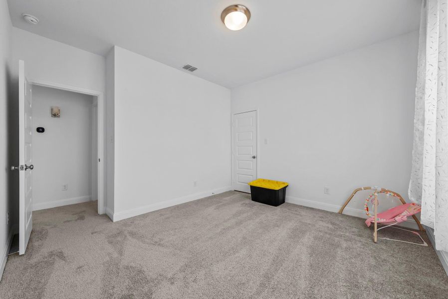Unfurnished bedroom with light carpet and baseboards