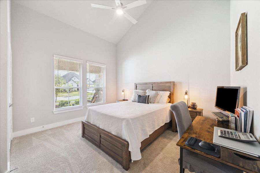 Bright and airy bedroom featuring large windows with blinds, a vaulted ceiling, and neutral-toned carpet. Bright and airy bedroom featuring large windows with blinds, a vaulted ceiling, and neutral-toned carpet.