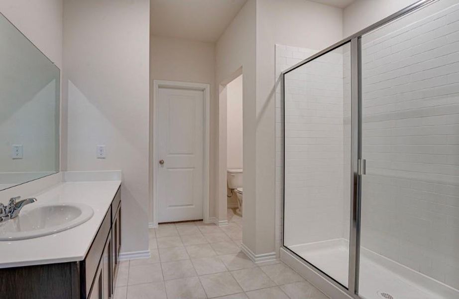 Bathroom featuring a glass-enclosed shower, white subway tile shower surround, dark wood vanity with white countertop, integrated sink, and chrome faucet Bathroom featuring a glass-enclosed shower, white subway tile shower surround, dark wood vanity with white countertop, integrated sink, and chrome faucet