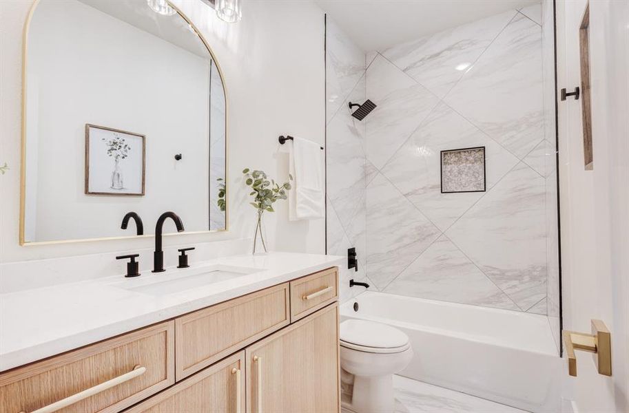 Full bathroom with vanity, tiled shower / bath combo, and toilet