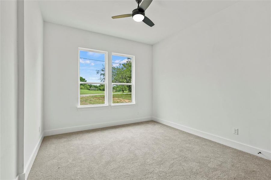 Carpeted empty room with baseboards and a ceiling fan