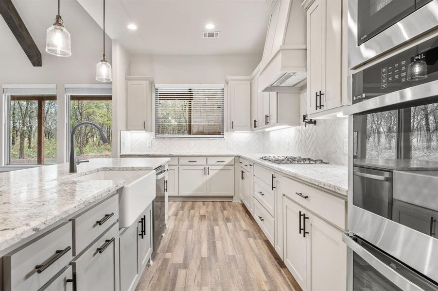 Kitchen featuring light hardwood / wood-style floors, sink, appliances with stainless steel finishes, white cabinets, and decorative backsplash