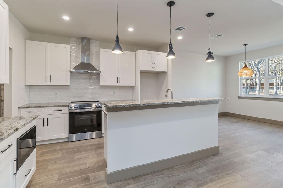 Kitchen with microwave built into lower cabinet, electric range and Viking vent hood