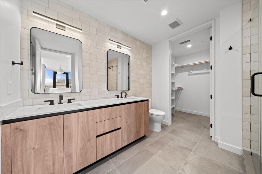 Primary bathroom with oversized floor tiles, a walk in shower, brass fixtures, and other luxurious features.