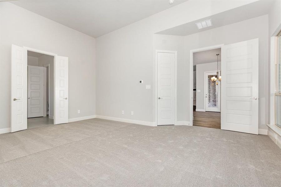Unfurnished bedroom featuring light colored carpet and a chandelier