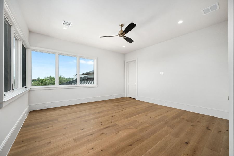 Natural light floods this spacious room, featuring elegant hardwood flooring and clear outdoor views.