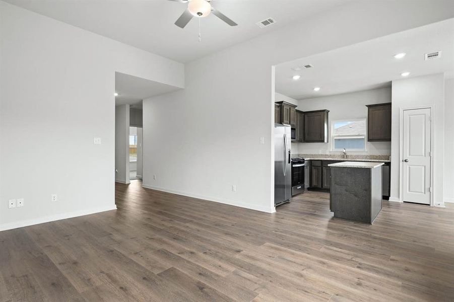 Kitchen with open floor plan, a kitchen island, dark wood-style flooring, dark brown cabinets, and a ceiling fan