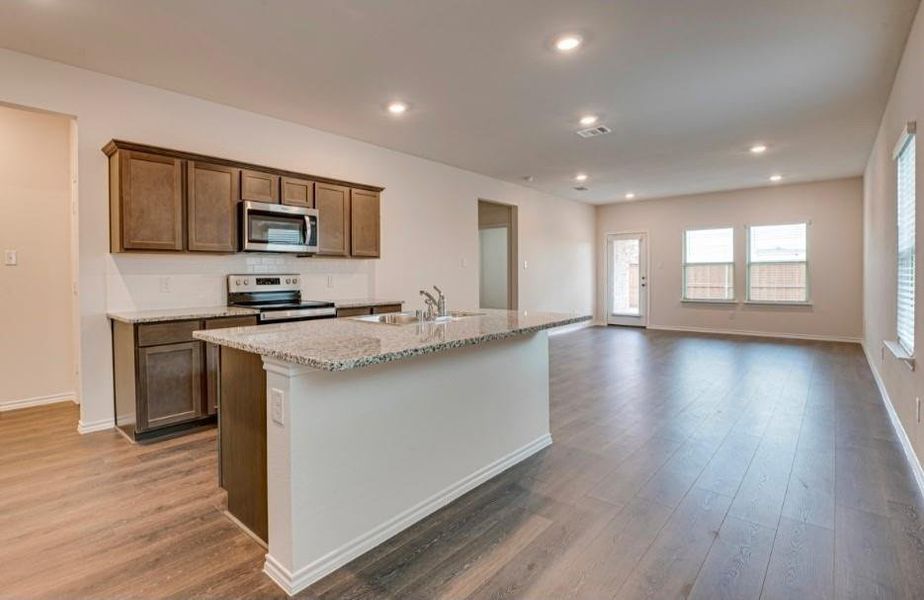 Modern kitchen featuring a central island with a granite-style countertop and integrated sink Modern kitchen featuring a central island with a granite-style countertop and integrated sink