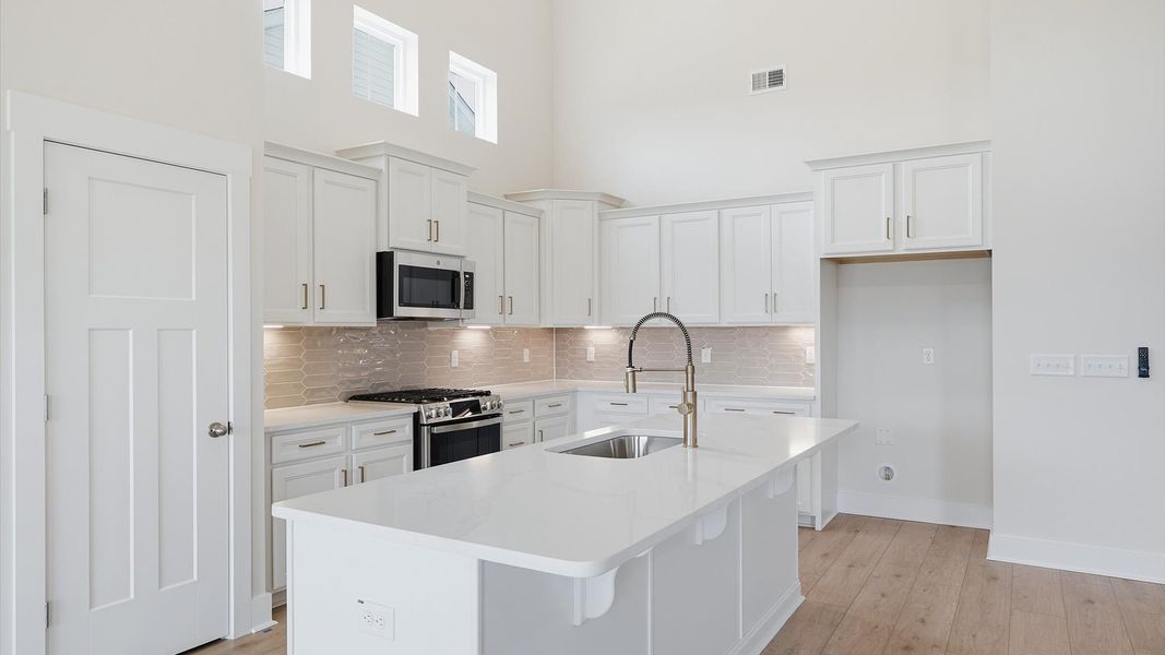 Tasteful kitchen with a streamlined island and modern finishes in a first-class DRB Homes design Tasteful kitchen with a streamlined island and modern finishes in a first-class DRB Homes design