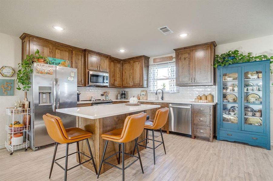 Kitchen with stainless steel appliances, a kitchen island, backsplash, a kitchen bar, and recessed lighting Kitchen with stainless steel appliances, a kitchen island, backsplash, a kitchen bar, and recessed lighting