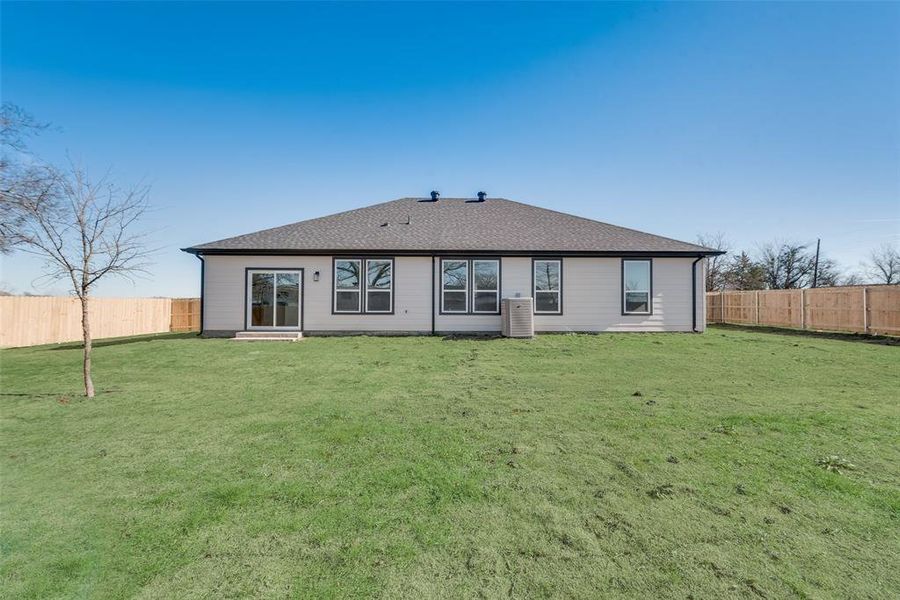 Rear view of house with a lawn and central AC unit