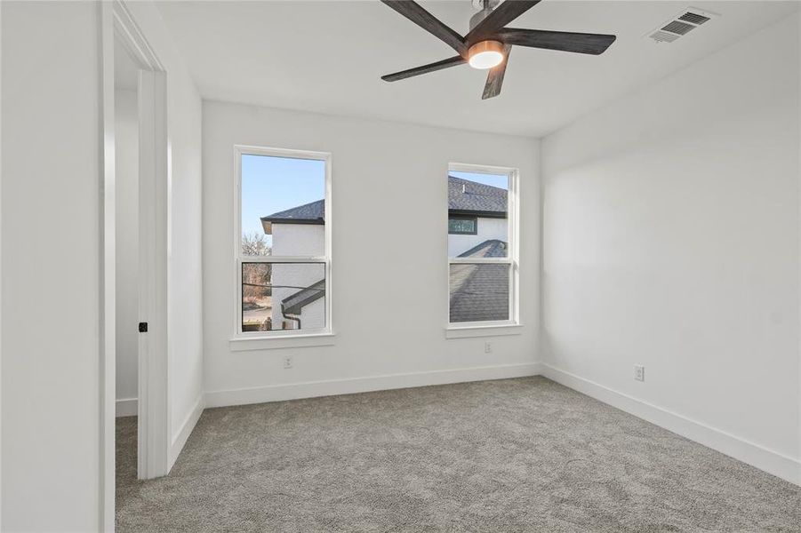 Spare room with light carpet, ceiling fan, visible vents, and baseboards