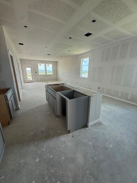 A spacious kitchen area awaiting finishing touches, featuring an island ready for customization.