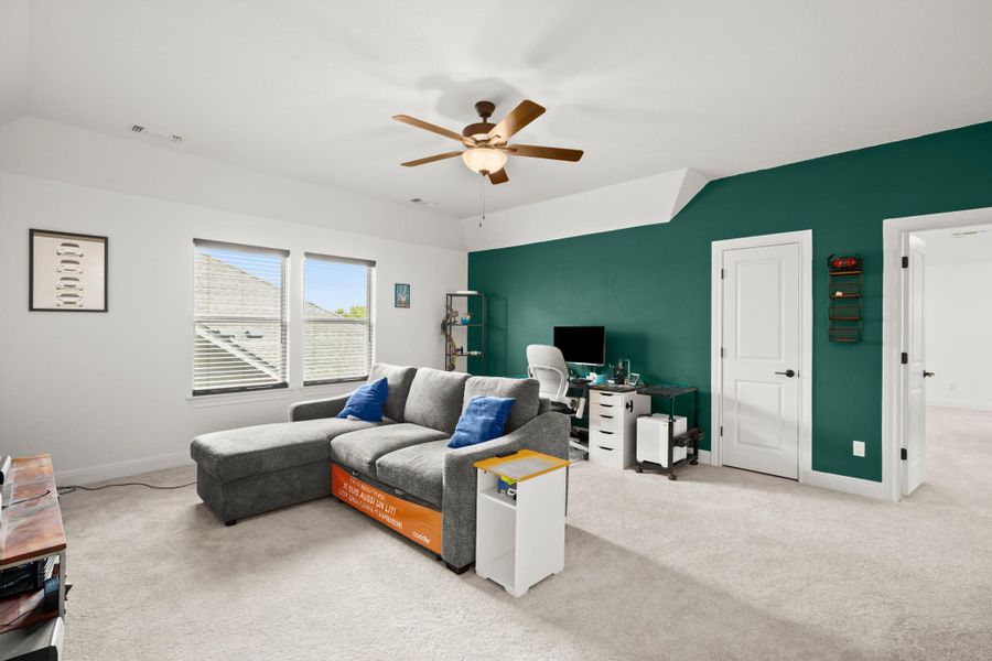 Living area with light carpet, ceiling fan, lofted ceiling, and an office area Living area with light carpet, ceiling fan, lofted ceiling, and an office area