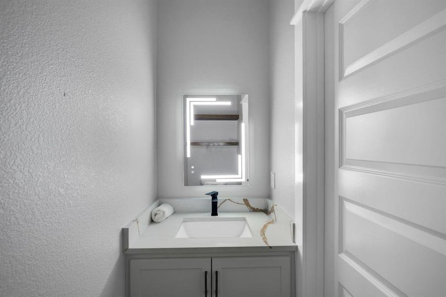 Guest hall bath with granite counters and modern mirror.