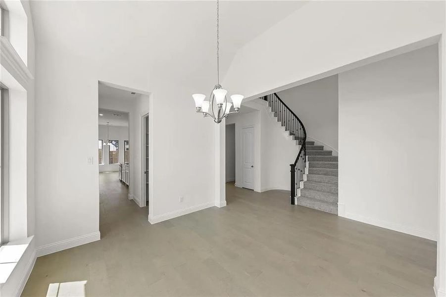 Unfurnished dining area with a high ceiling and an inviting chandelier