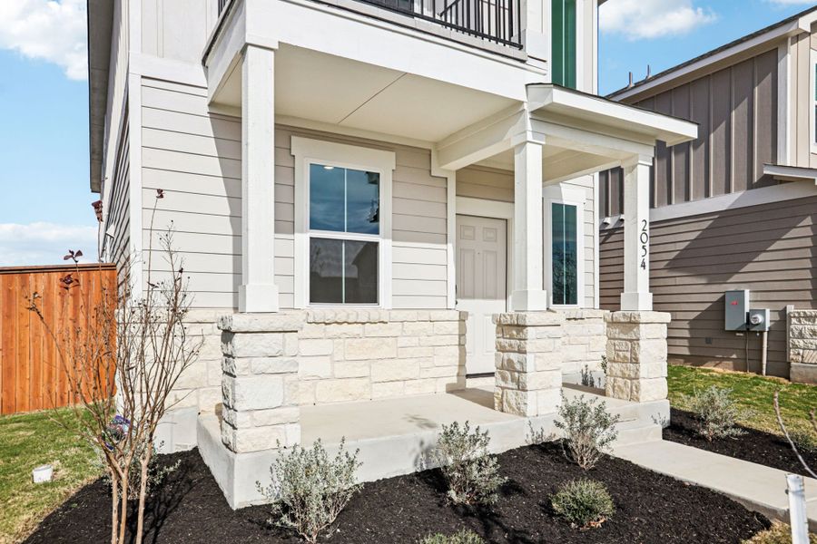 A white house with a stone wall.