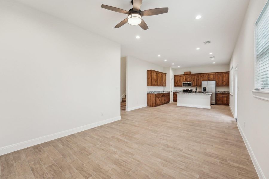 Unfurnished living room featuring stairway, baseboards, recessed lighting, ceiling fan, and wood plank tile floor Unfurnished living room featuring stairway, baseboards, recessed lighting, ceiling fan, and wood plank tile floor