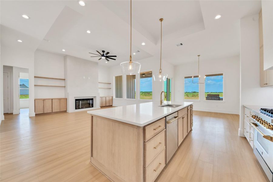Open-concept kitchen featuring an oversized island, quartz countertops, elegant pendant lighting, and seamless flow into the family room. Open-concept kitchen featuring an oversized island, quartz countertops, elegant pendant lighting, and seamless flow into the family room.