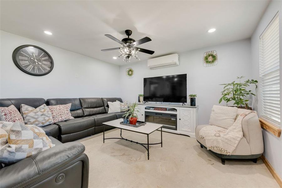 Living room featuring baseboards, recessed lighting, carpet flooring, a ceiling fan, and a wall unit AC