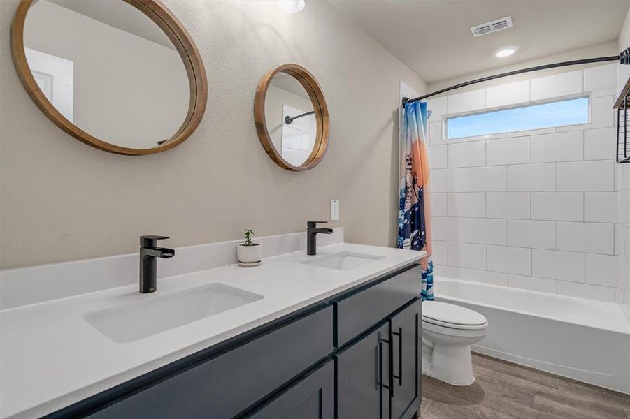 Bathroom with double vanity, light wood-style flooring, and shower / bath combination with curtain