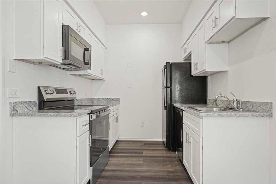 Kitchen featuring light stone countertops, appliances with stainless steel finishes, dark wood-type flooring, sink, and white cabinetry