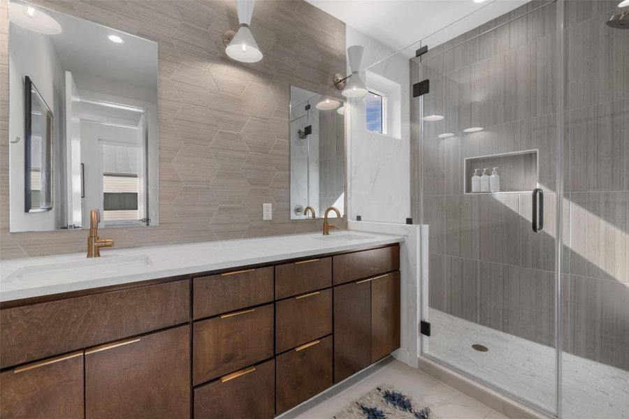 Bathroom featuring double vanity, a shower stall, and tile walls