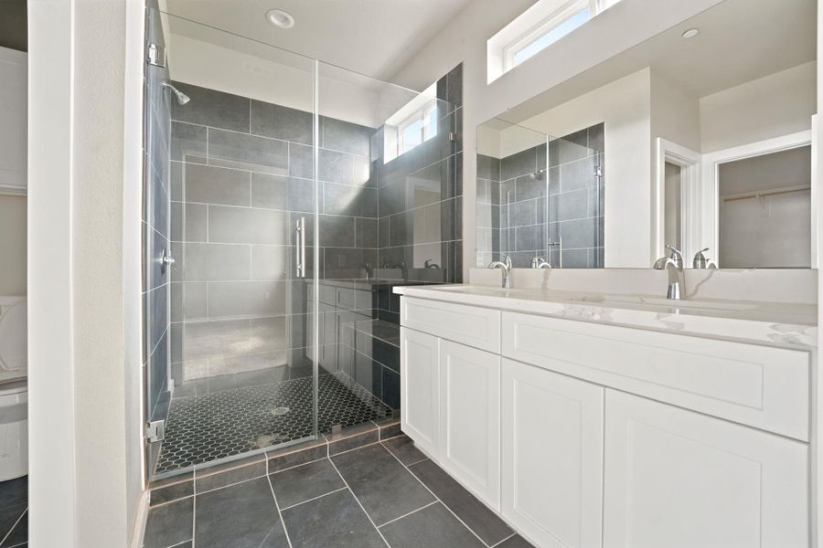 Sleek slate flooring and a glass-enclosed walk-in shower highlight this modern bathroom design.
