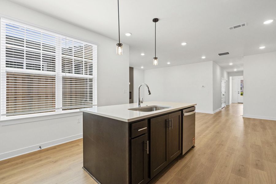 Kitchen island featuring a stainless steel sink, gooseneck faucet, and integrated dishwasher