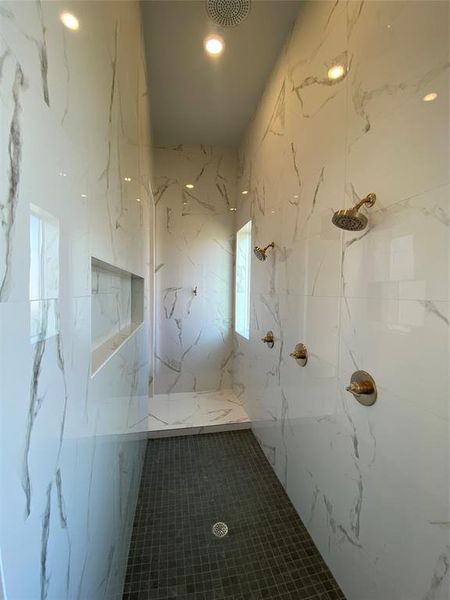 Bathroom featuring a marble finish shower, recessed lighting, and stone wall