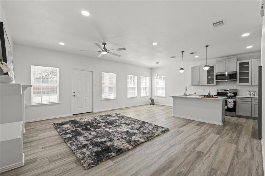 Kitchen with open floor plan, gray cabinetry, visible vents, and stainless steel appliances