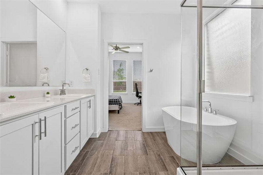 Spacious bathroom featuring a freestanding soaking tub, walk-in shower with glass enclosure, dual vanity with undermount sinks, and wood-finish flooring