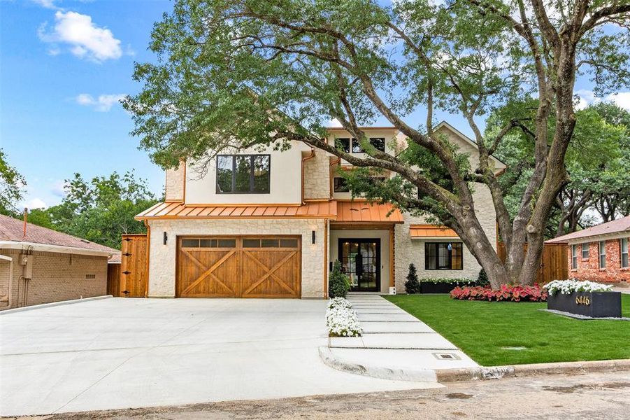 View of front of property featuring a standing seam roof, concrete driveway, an attached garage, and a front lawn