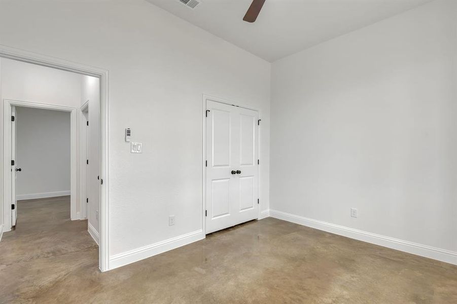 Unfurnished bedroom with concrete floors, a closet, and a ceiling fan