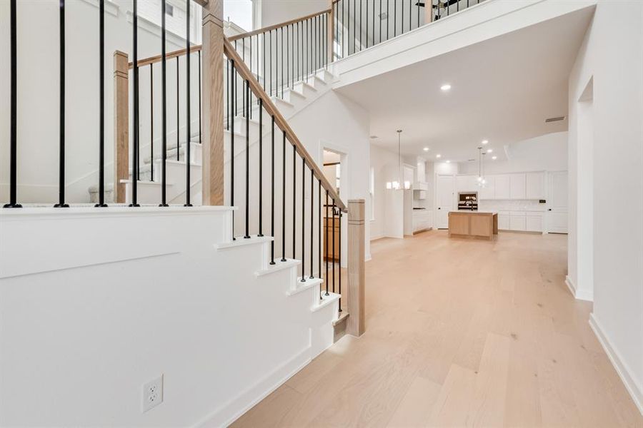 Stairs featuring recessed lighting, wood finished floors, and a towering ceiling Stairs featuring recessed lighting, wood finished floors, and a towering ceiling